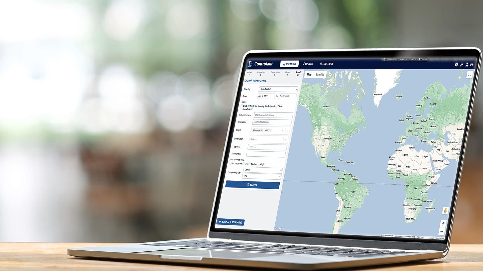 A laptop on a wooden table showing the platform's shipment search and a world map