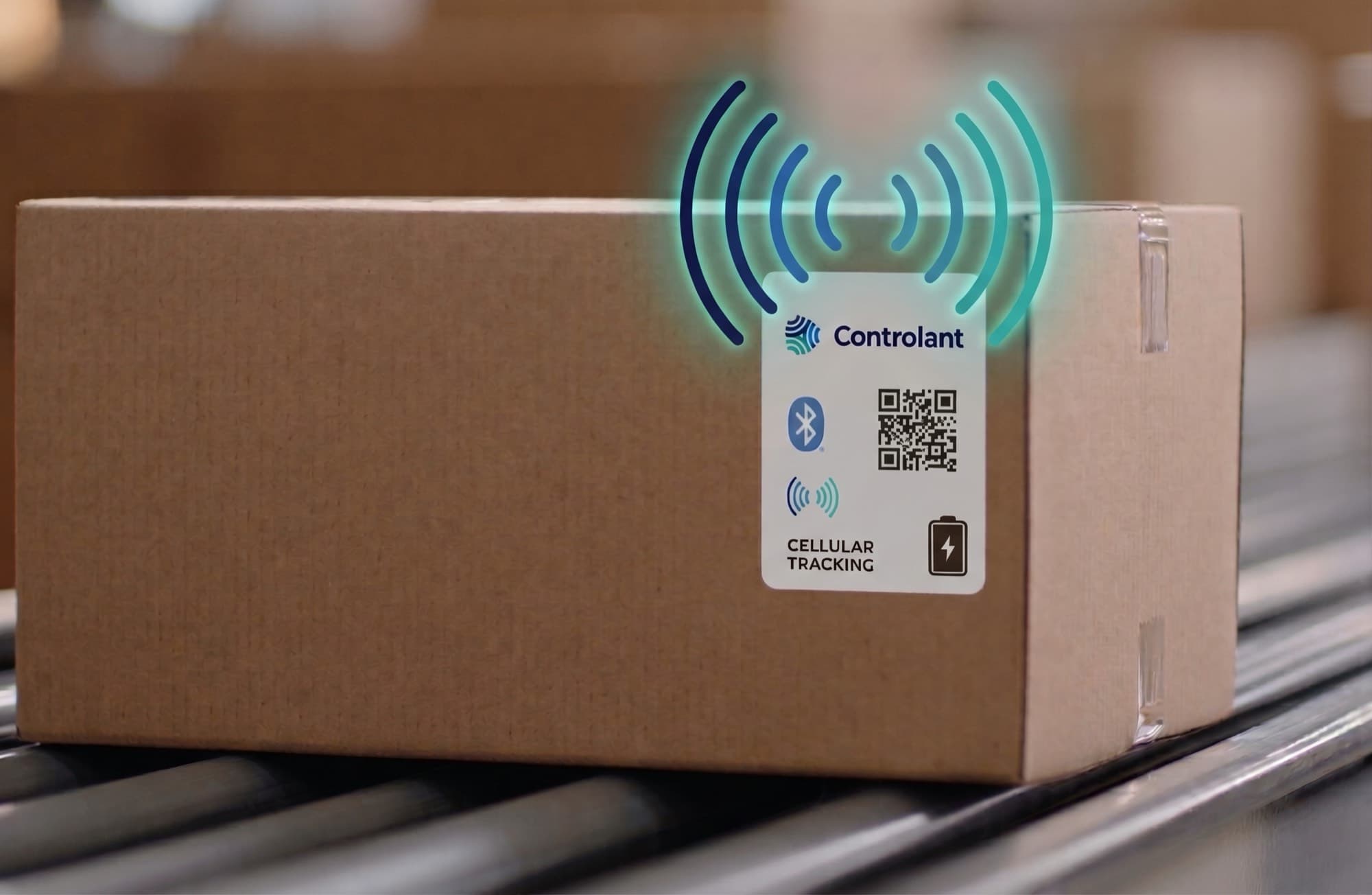 A cardboard carton on a conveyor with a white Controlant label on its side, printed with a Bluetooth symbol, a QR code, a battery symbol and the words Cellular tracking, under drawn signal arcs