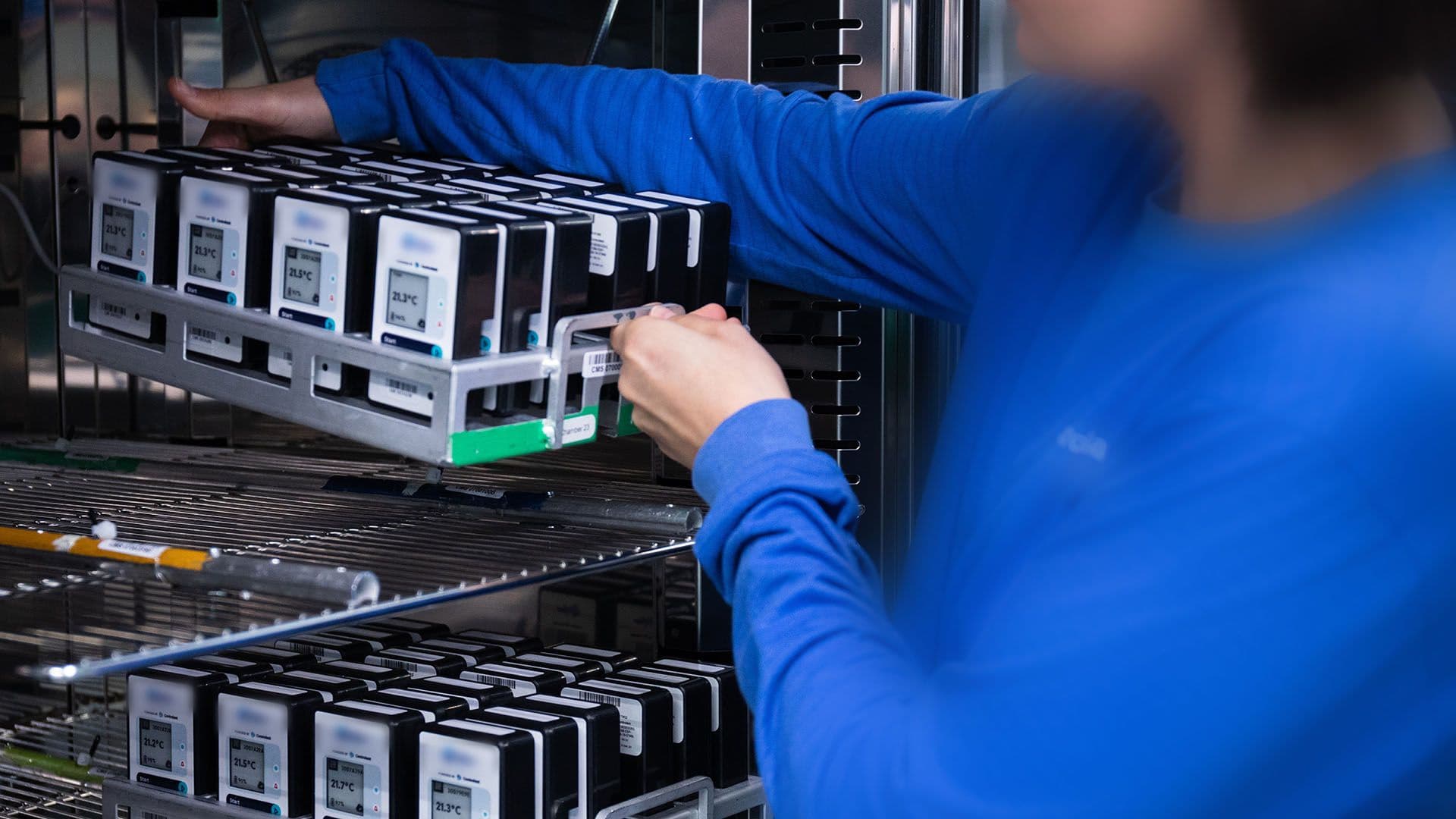 A technician loading racks of Saga devices into a test chamber